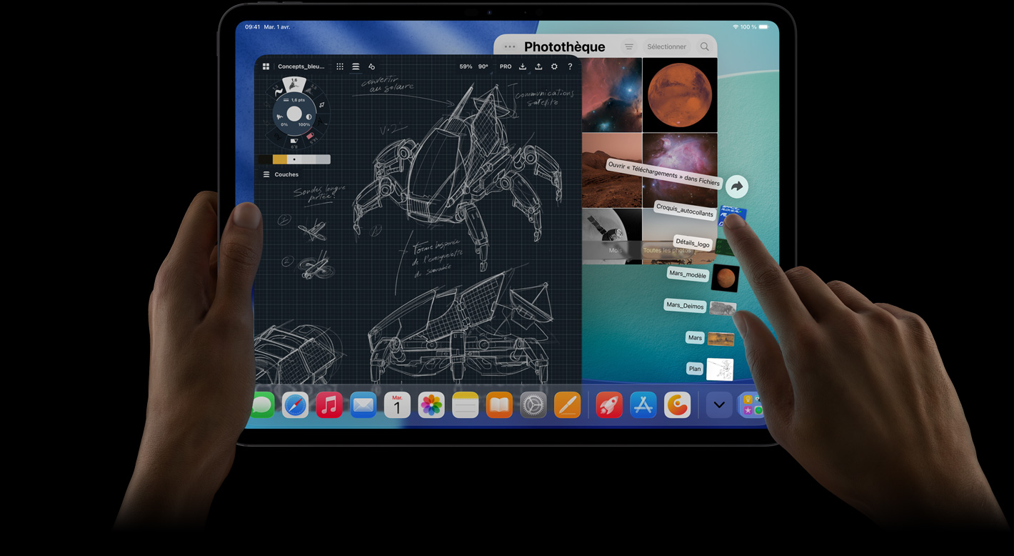 Un iPad Pro, face avant, orientation paysage, main droite qui fait un geste au-dessus des éléments du dossier de téléchargement qui se déploient, écran affichant l’interface d’iPadOS 26 avec plusieurs apps ouvertes, y compris une app de retouche photo montrant des plans détaillés de robots, des annotations manuscrites et plusieurs étapes de conception, et la photothèque