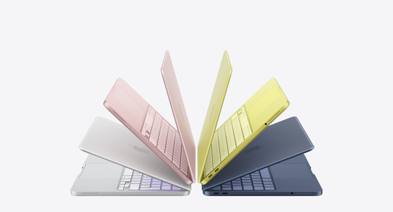 Des portables MacBook Neo de couleur argent, rose pastel, agrume et indigo, entrouverts et disposés en arc de cercle