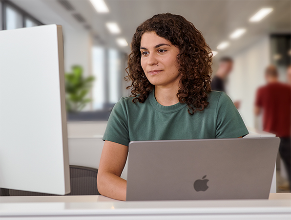 Una persona del equipo de Apple usa una MacBook con Studio Display en una oficina.
