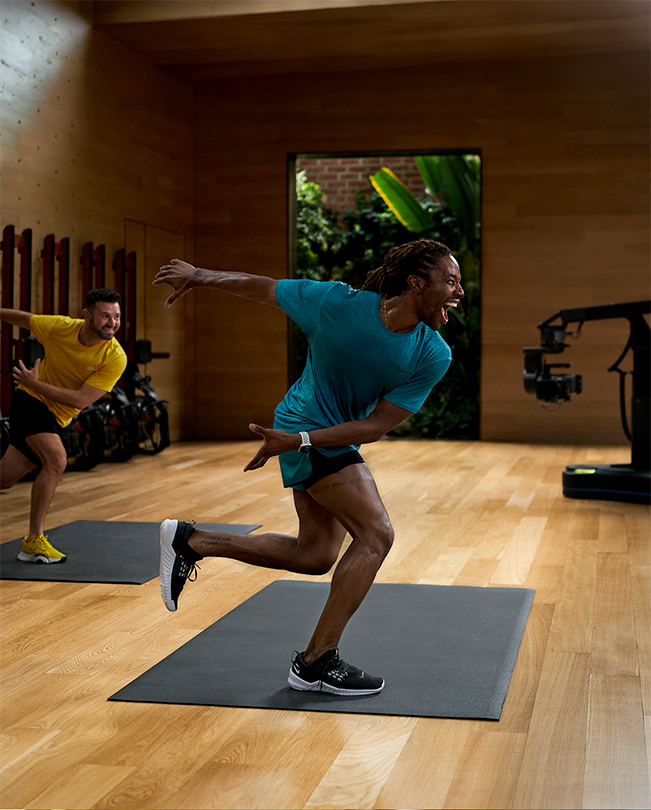 Due trainer Apple Fitness+ che tengono un corso davanti ad alcune videocamere in uno studio di registrazione. 