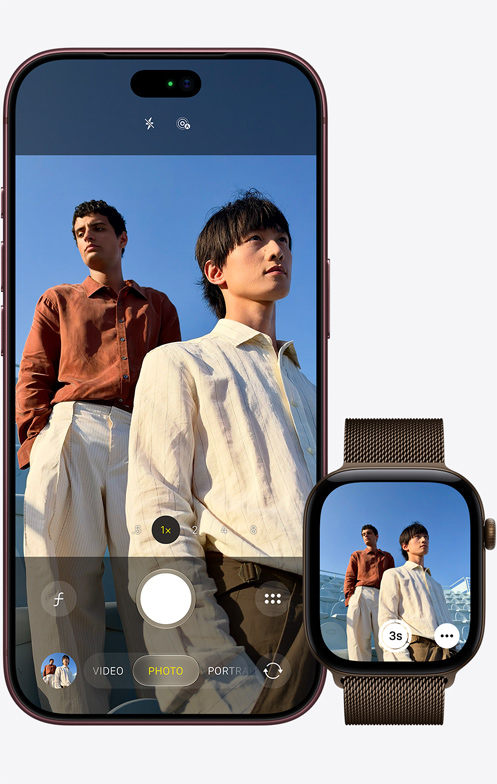 iPhone 18 Pro elölnézetből, a kamerája két férfiről készít felvételt kék égbolttal a háttérben, az iPhone mellett egy Apple Watch Ultra 3, amelyen a Kamera-távirányító app van megnyitva.