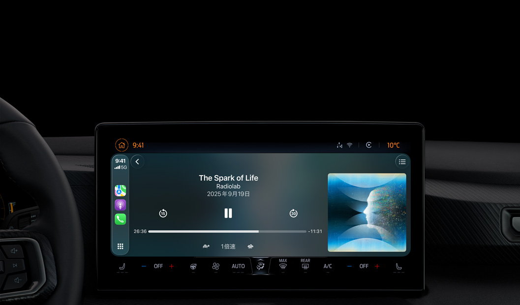 車の内部、センターコンソールのディスプレイにCarPlay経由でApple Podcastの再生が表示されている。Radiolabの「The Spark of Life」のポッドキャストが現在再生されており、再生コントロールには早戻し、一時停止、スキップがある