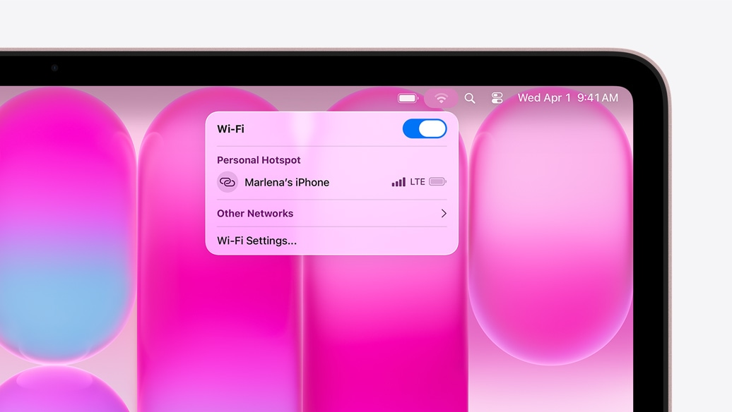 Rausvas „MacBook Neo“, „Wi‑Fi“ meniu rodomas asmeninis interneto prieigos taškas su užrašu „Marlena's iPhone“ kaip pasirinkimo galimybė
