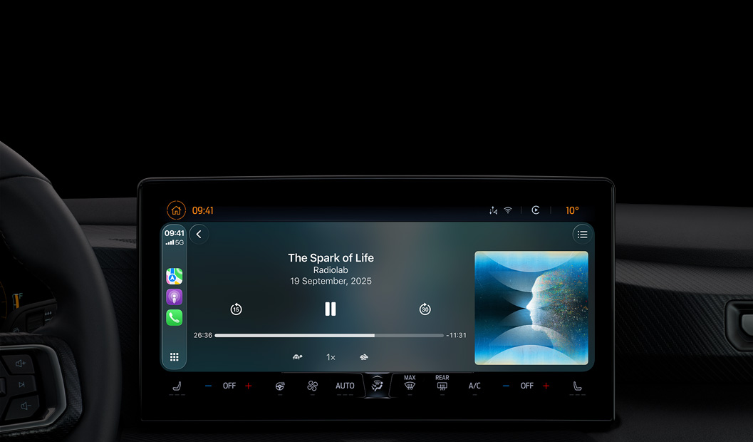 A car interior, center console display shows Apple Podcasts playing via CarPlay, now playing "The Spark of Life" podcast by Radiolab, playback controls include skip back, pause, and skip forward.