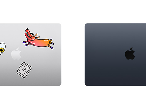A top down view of two closed Mac laptops, one with stickers.