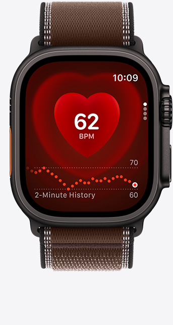 Apple Watch Ultra 4, screen shows Heart Rate app, current beats per minute, titanium case, black colour, connected to Trail Loop strap, dark umber colour (brown)