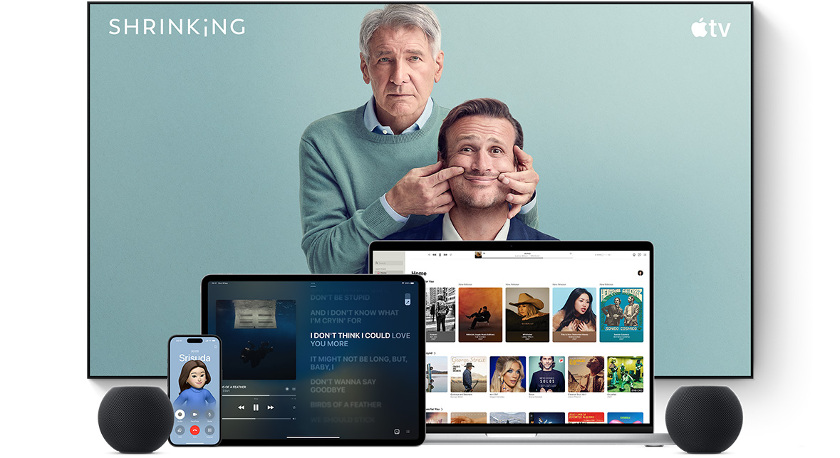 ทีวีจอแบนขนาดใหญ่แสดงตัวละครชายสองคนจากซีรีส์เรื่อง Shrinking ของ Apple TV โดยมี MacBook Pro, iPad, iPhone และ HomePod mini สีมิดไนท์วางอยู่ด้านหน้า