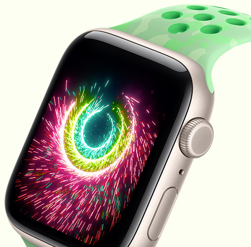 スターライトアルミニウムケースのApple Watch SE 3。画面に花火のように輝くアクティビティリングが表示されている。グリーンスパーク（ミントグリーン、グレイの図形による目立たない模様、丸い通気穴）のNikeスポーツバンドが取りつけられている