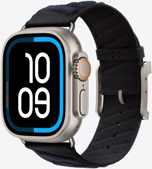 Apple Watch Hermès Ultra 3, caja de titanio, color natural, pantalla de borde a borde, esquinas redondeadas, parte lateral derecha, Digital Crown, micrófono, botón lateral en relieve, carátula Maritime digital (marca las 10:09), con la correa En Mer, color Noir/Bleu Nuit (negro con franjas diagonales en tono azul oscuro), fabricada con hilo de poliamida tejido, orificios de ajuste en el centro, hebilla y componentes de titanio natural