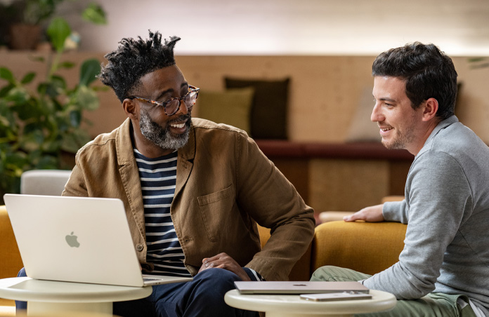 MacBook open on a table in front of a person smiling