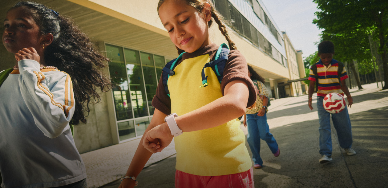 Close-up of a child wearing a backpack using an Apple Watch.