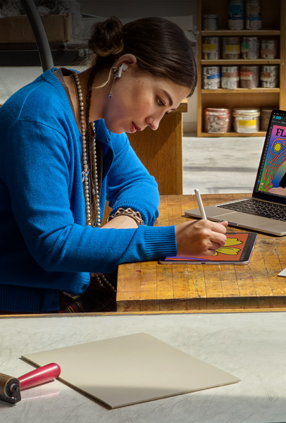 兩名學生在宿舍房間透過銀色 MacBook 瀏覽內容，其中一個人坐在床上，另一人則坐在地板上拿著筆電