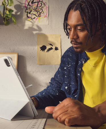 Egy férfi irodai környezetben 12,9 hüvelykes, ezüstszínű iPad Prót használ