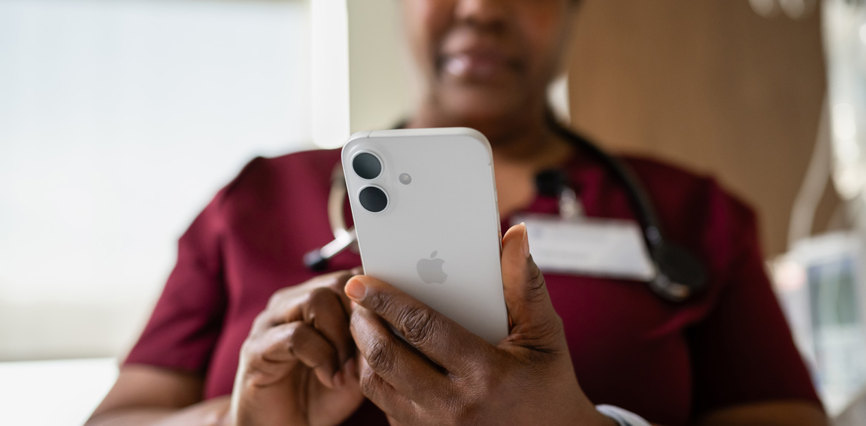 Una enfermera con una bata roja mira su iPhone.