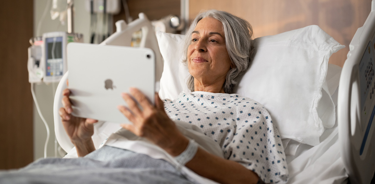 Una paciente mira su iPad en la cama de un hospital.