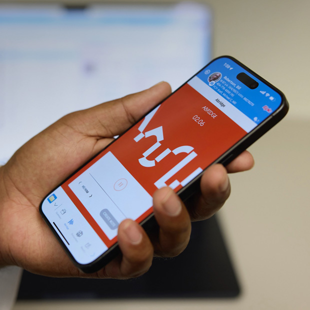 Una mano sujeta un iPhone con Abridge, una app que convierte las conversaciones entre los equipos médicos y los pacientes en notas clínicas.