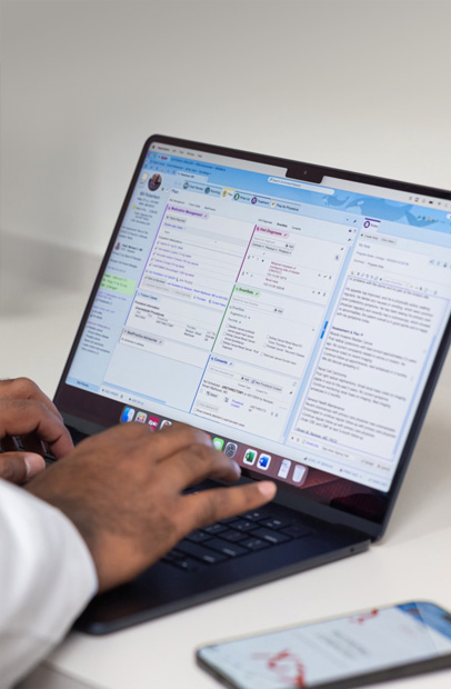 Una persona de un equipo sanitario consulta historiales clínicos digitales en un MacBook Pro.