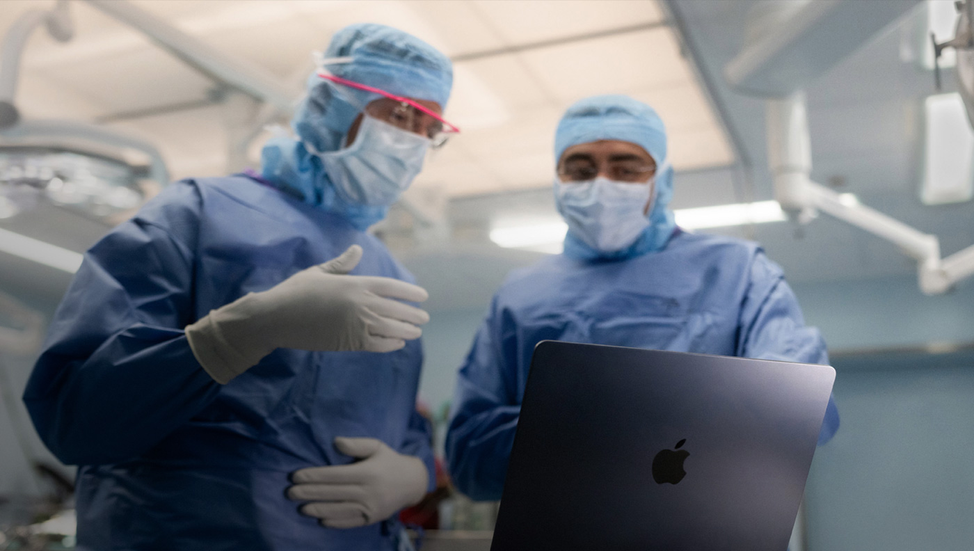 Dos personas en un quirófano comentan lo que aparece en la pantalla de un MacBook Pro.