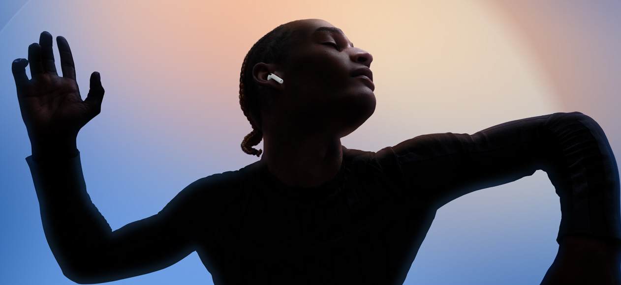 A person wearing AirPods 4 while dancing with their eyes closed and their head tilted upwards.