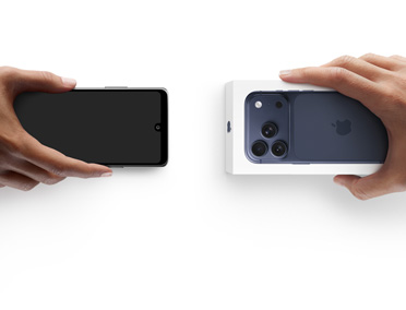 スマートフォンを交換する2つの手。左側に箱のないAndroidスマートフォンがあり、右側に箱に入った新しいiPhone 17 Proがある