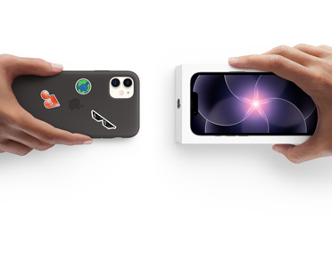 Two hands side-by-side, hand holding iPhone 11 in Silicone Case with stickers on back exterior, trade-in with hand holding new iPhone 17e box