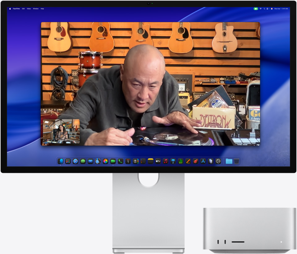 While on a video call on Studio Display XDR with Mac Studio tucked underneath, a person at a music store looks closely at a turntable